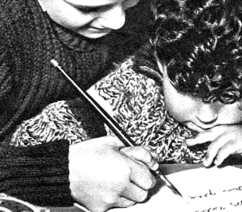 Un niño ayuda a su hermanito a escribir la carta a los Reyes Magos.