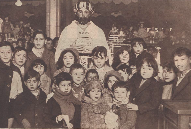 Niños junto al muñeco de un rey mago con un buzón