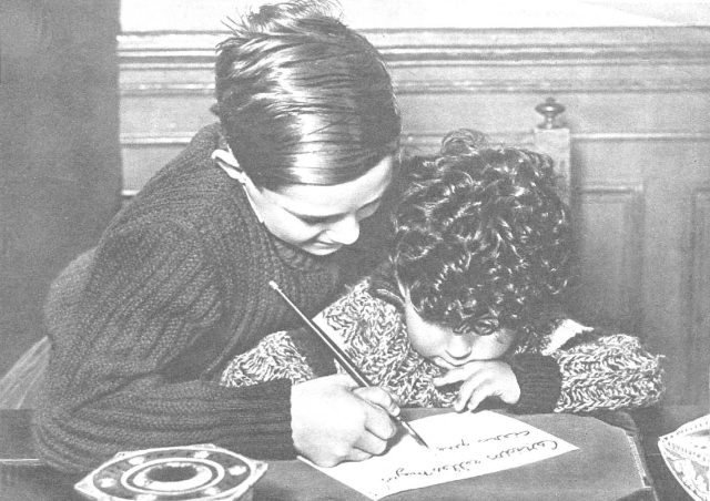 Un niño ayuda a su hermanito a escribir la carta a los Reyes Magos
